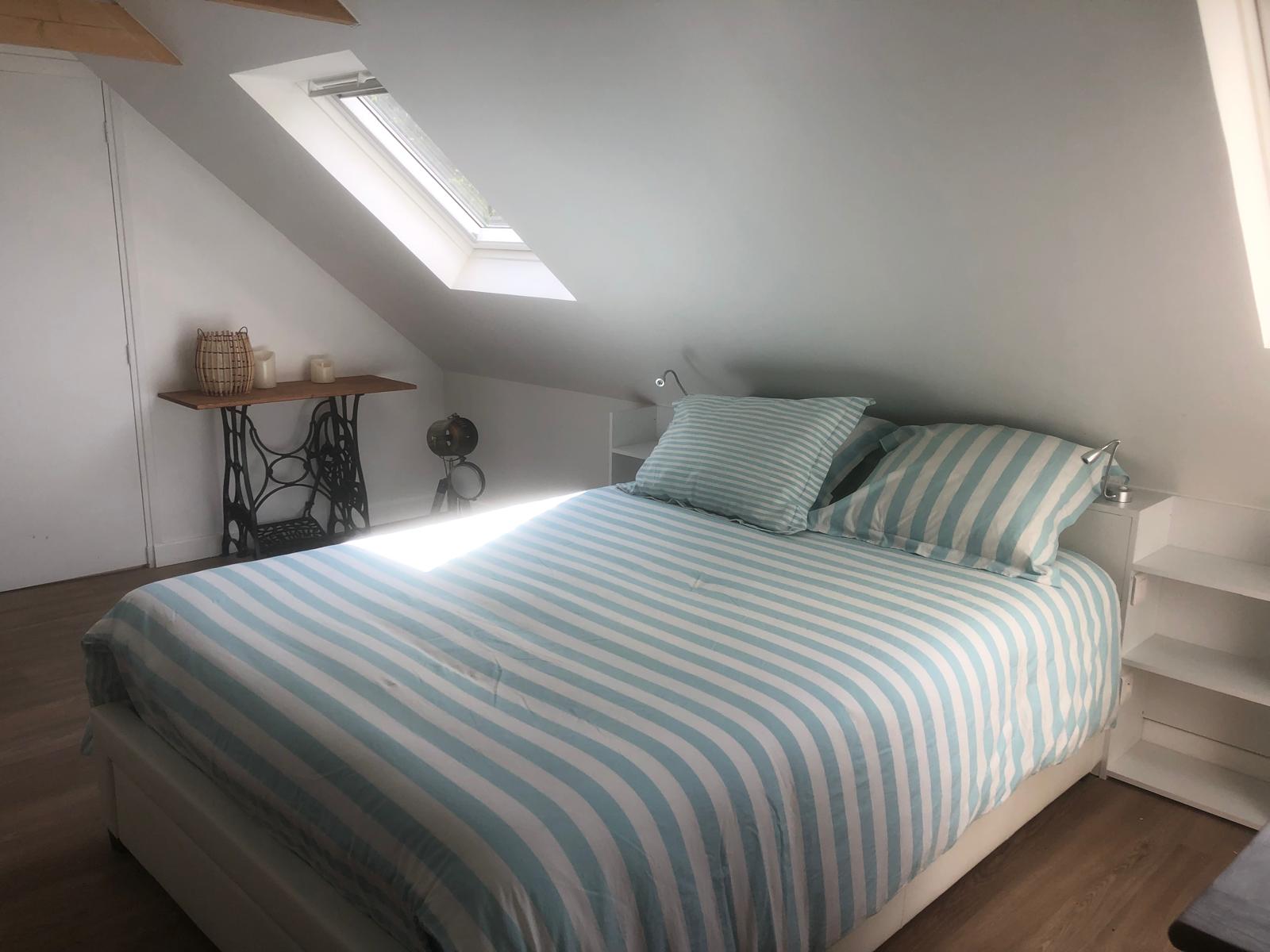 Chambre mansardée avec lit double et décoration bleue
