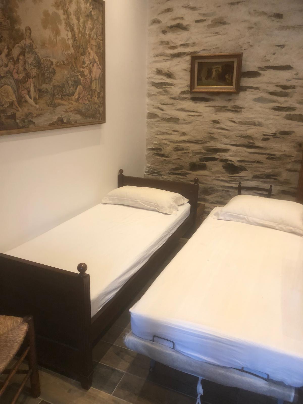 Chambre avec lits jumeaux et mur en pierre apparente