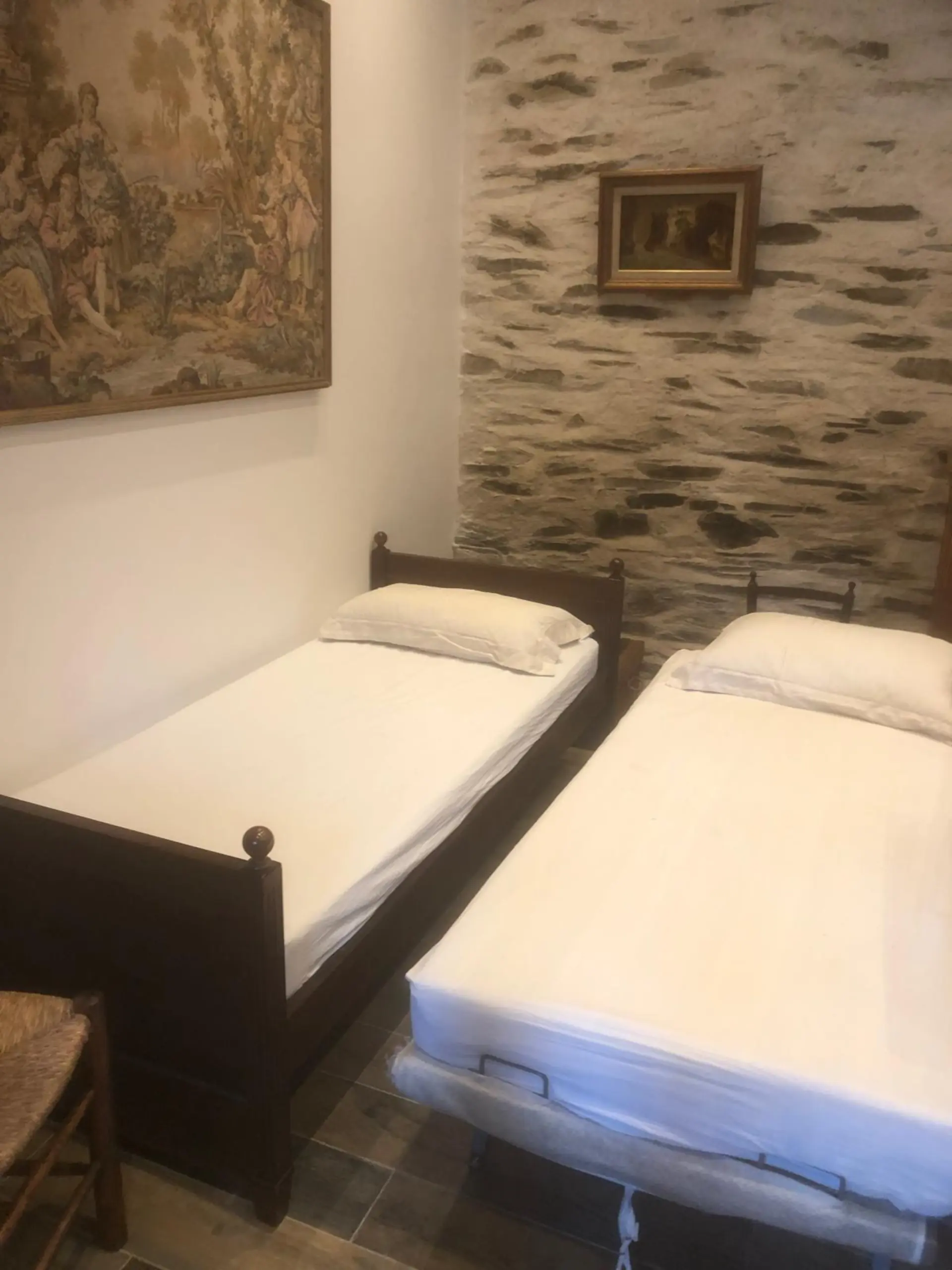 Chambre avec lits jumeaux et mur en pierre apparente