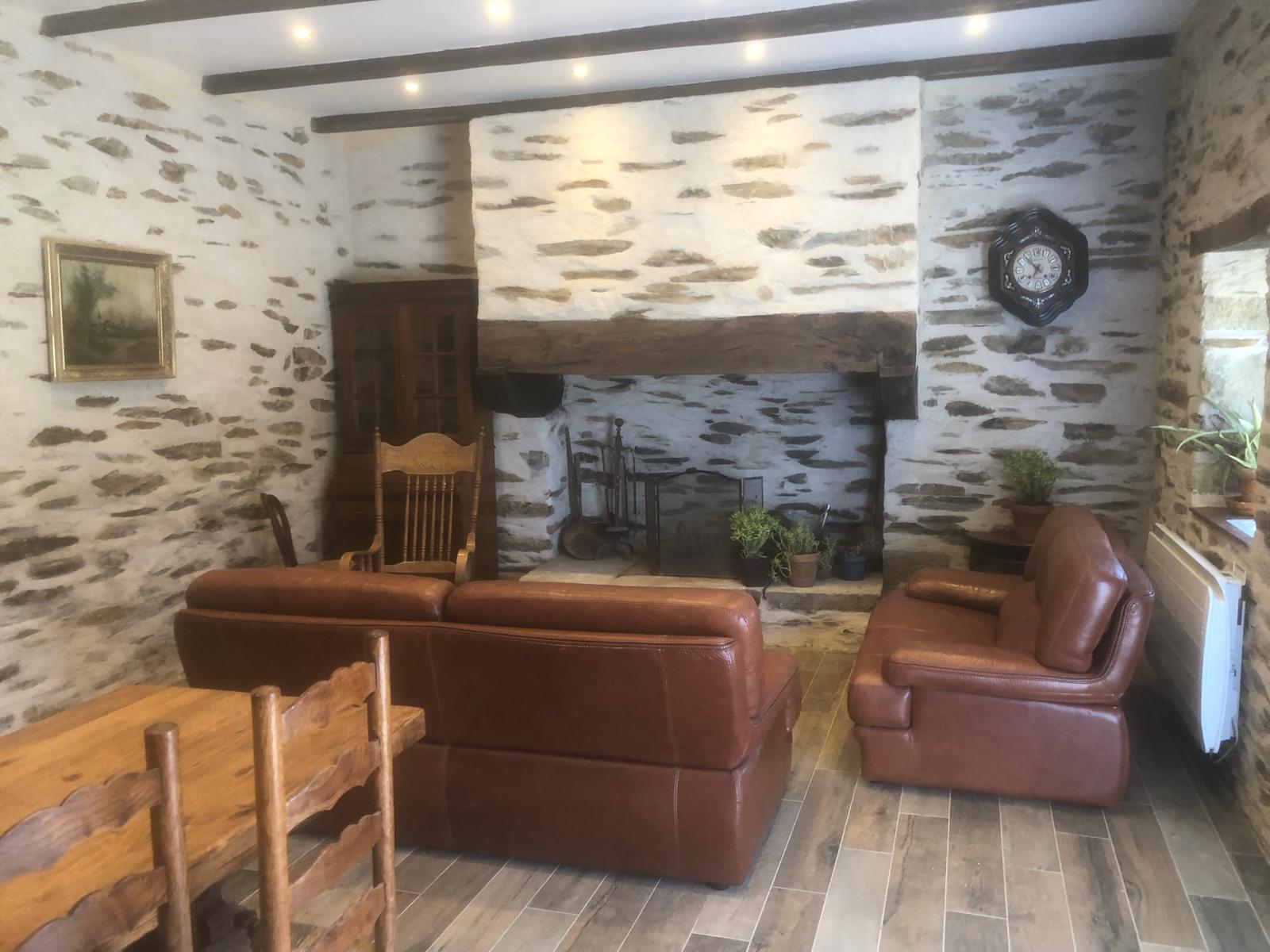 Coin cheminée avec fauteuils en cuir dans le salon du gîte