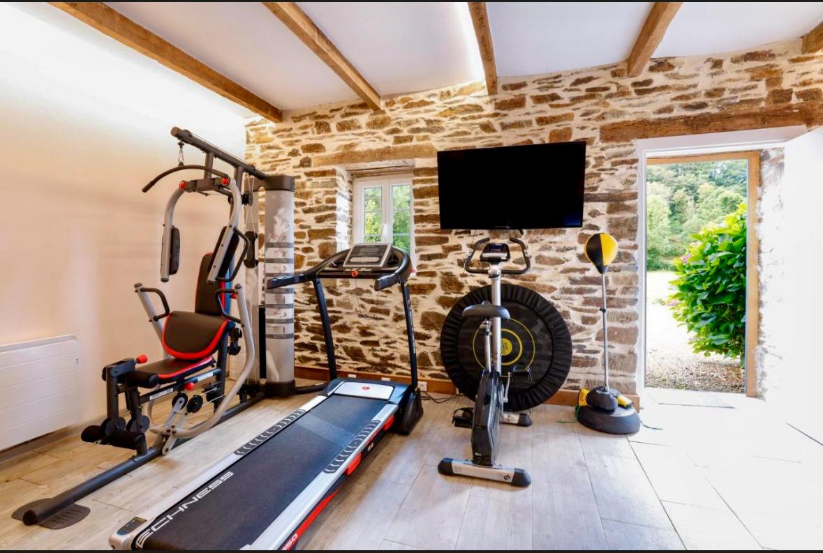 Salle de fitness complete avec murs en pierre