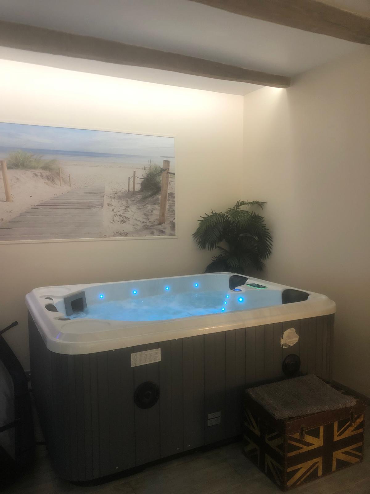 Jacuzzi illuminé avec jets dans l'espace spa privatif en pierre